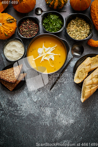 Image of Delicious pumpkin soup with cream, seeds, bread and fresh herbs 