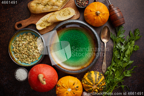 Image of Empty ceramic bowl and ingredients ready for pumpkin soup. With different kinds of small pumpkins