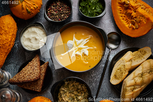 Image of Delicious pumpkin soup with cream, seeds, bread and fresh herbs 