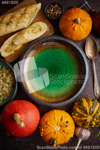 Image of Empty ceramic bowl and ingredients ready for pumpkin soup. With different kinds of small pumpkins