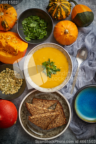 Image of Pumpkin soup decorated with parsley for Thanksgiving, halloween. Placed on grey stone background
