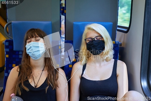 Image of Young women on a train wearing masks
