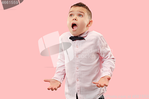 Image of The young attractive teen boy looking suprised isolated on pink