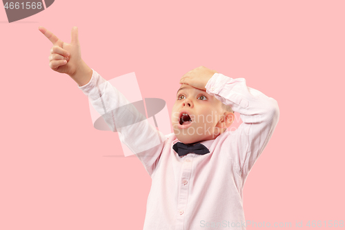 Image of The young attractive teen boy looking suprised isolated on pink