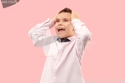 Image of The young attractive teen boy looking suprised isolated on pink