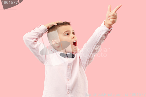 Image of The young attractive teen boy looking suprised isolated on pink