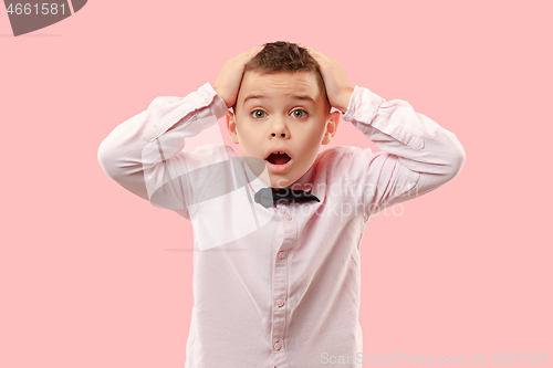 Image of The young attractive teen boy looking suprised isolated on pink