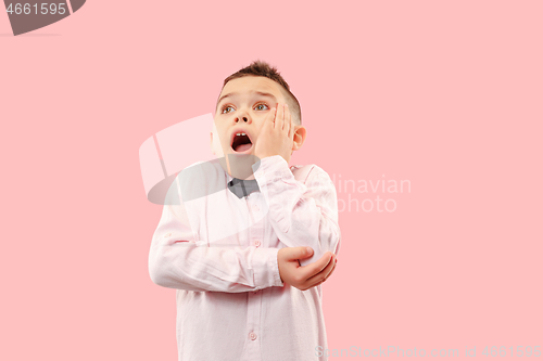 Image of The young attractive teen boy looking suprised isolated on pink