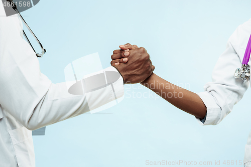 Image of The female and male hands of afro american doctors on blue background