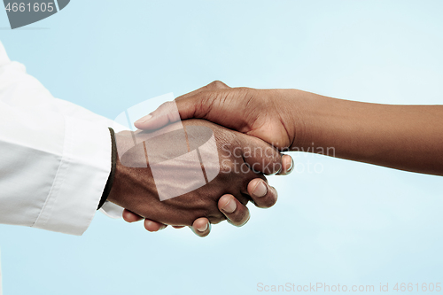 Image of The female and male hands of afro american doctors on blue background