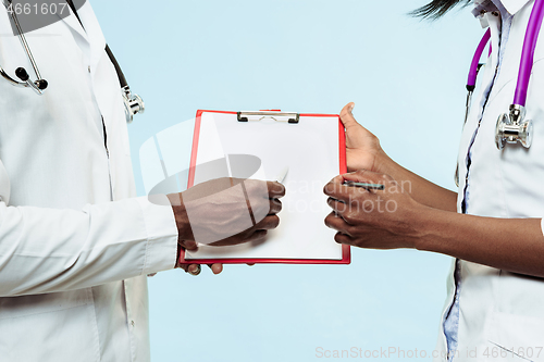 Image of The female and male hands of afro american doctors on blue background