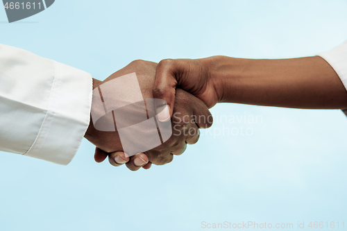 Image of The female and male hands of afro american doctors on blue background