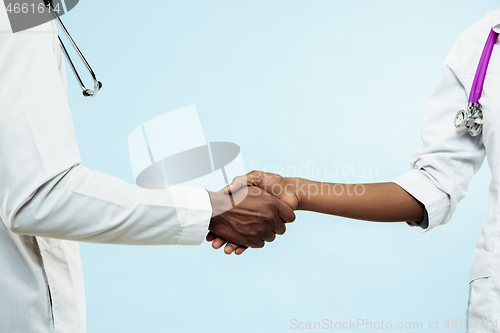 Image of The female and male hands of afro american doctors on blue background