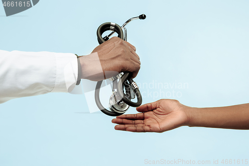 Image of The female and male hands of afro american doctors on blue background