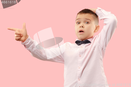 Image of The young attractive teen boy looking suprised isolated on pink