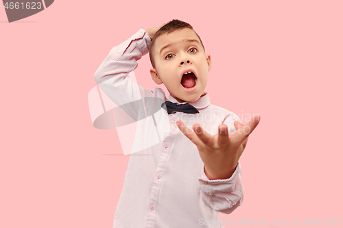 Image of The young attractive teen boy looking suprised isolated on pink