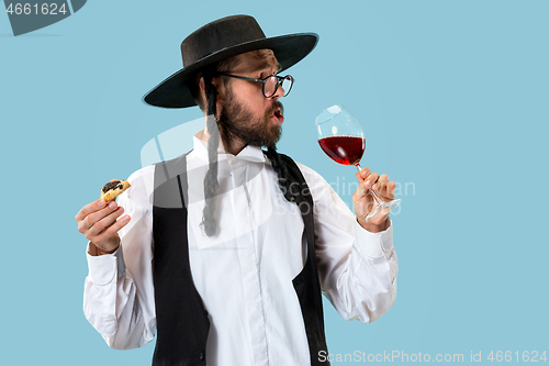 Image of The young orthodox Jewish man with black hat with Hamantaschen cookies for Jewish festival of Purim