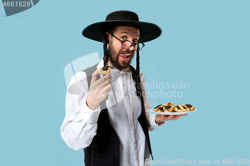 Image of The young orthodox Jewish man with black hat with Hamantaschen cookies for Jewish festival of Purim