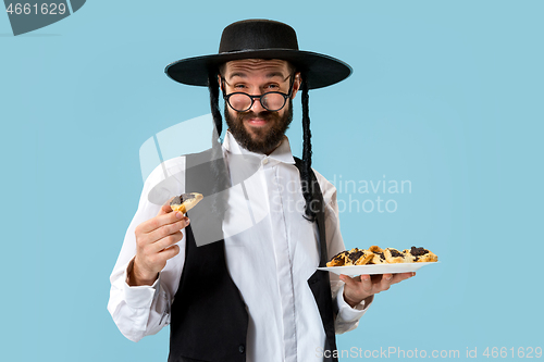 Image of The young orthodox Jewish man with black hat with Hamantaschen cookies for Jewish festival of Purim