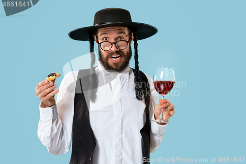 Image of The young orthodox Jewish man with black hat with Hamantaschen cookies for Jewish festival of Purim