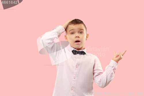 Image of The young attractive teen boy looking suprised isolated on pink