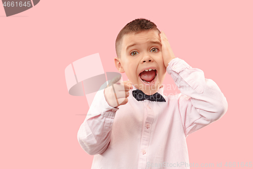 Image of The young attractive teen boy looking suprised isolated on pink