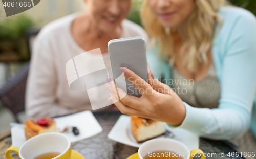 Image of daughter and senior mother taking selfie at cafe