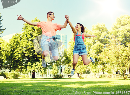 Image of happy teenage couple jumping at summer park