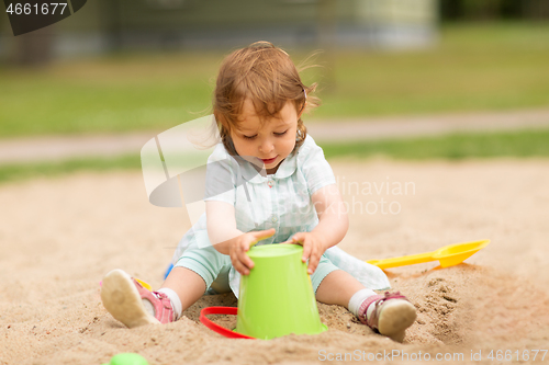 Image of little baby girl plays with toys in sandbox