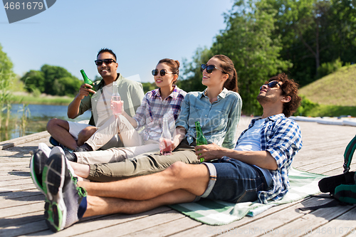 Image of friends drinking beer and cider on lake pier