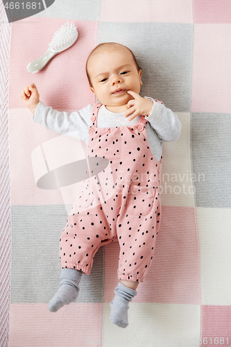Image of sweet baby girl in pink suit lying on blanket
