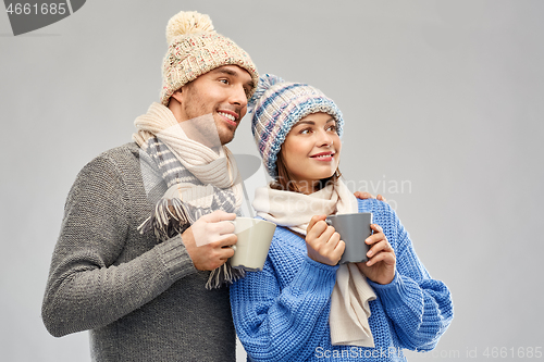 Image of happy couple in winter clothes with mugs
