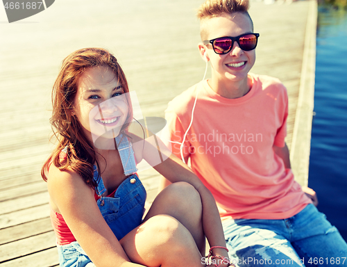 Image of happy teenage couple with earphones on river berth