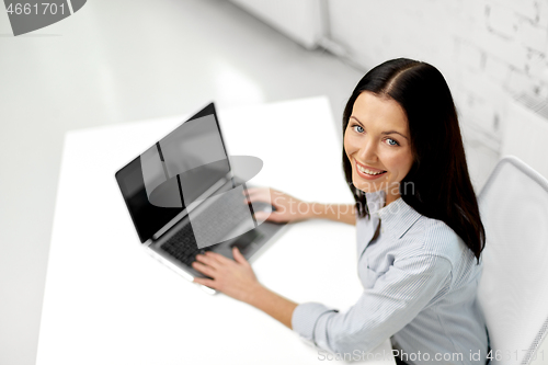 Image of smiling businesswoman with laptop at office