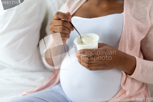 Image of pregnant woman eating yogurt for breakfast in bed