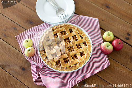 Image of apple pie in baking mold on wooden table