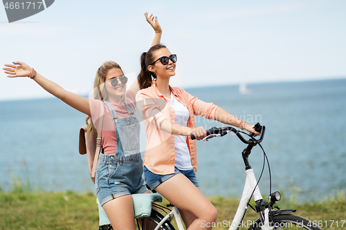 Image of teenage girls or friends riding bicycle in summer