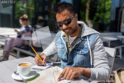 Image of man with map and notebook at street cafe in city
