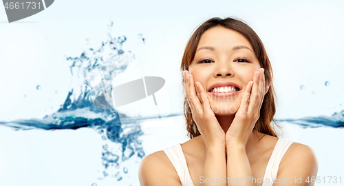 Image of happy smiling young asian woman touching her face