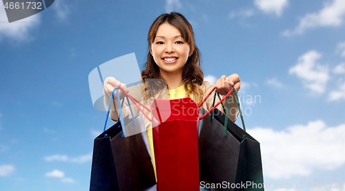 Image of happy asian woman with open shopping bags