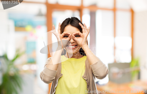 Image of smiling asian woman looking through finger glasses