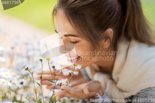 Image of close up of woman smelling chamomile flowers