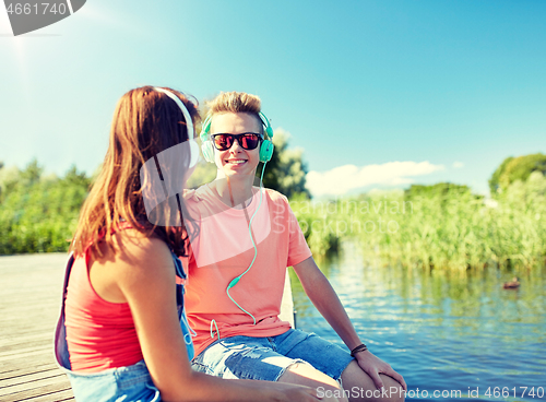 Image of happy teenage couple with earphones on river berth