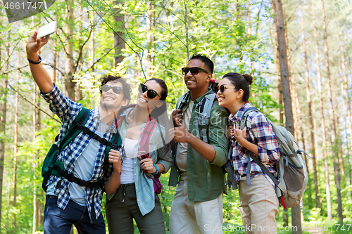 Image of friends with backpacks hiking and taking selfie