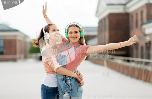 Image of teenage girls or friends in headphones in city