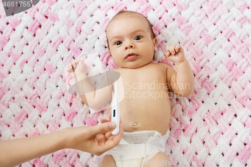 Image of mother\'s hand measuring temperature of baby girl