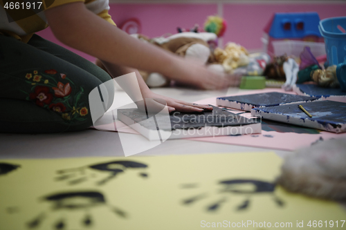 Image of cute little girl at home painting with hands