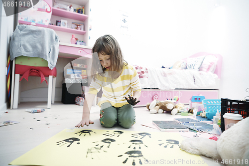 Image of cute little girl at home painting with hands