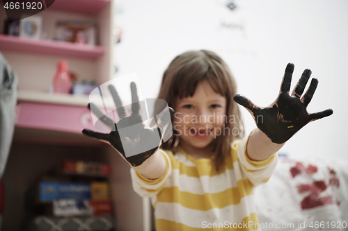 Image of cute little girl at home painting with hands