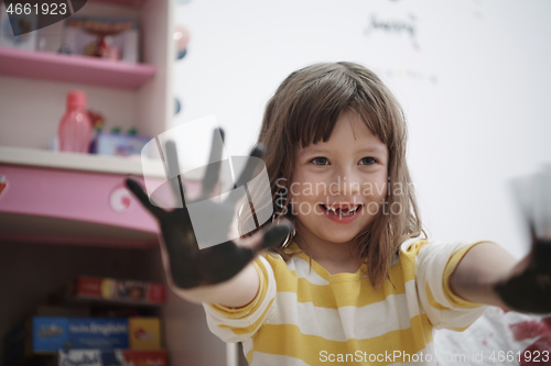 Image of cute little girl at home painting with hands